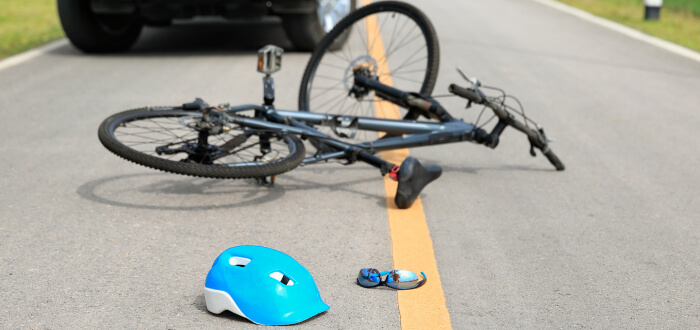 A bike lays on the road along with a helmet and sunglasses
